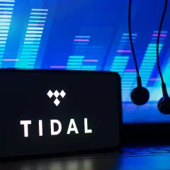 Smartfon z logo TIDAL i słuchawkami na tle wykresu dźwiękowego.