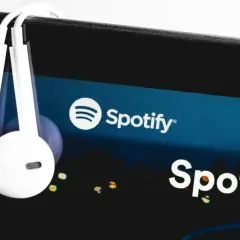 Słuchawki wiszące na ekranie smartfona z logo Spotify.