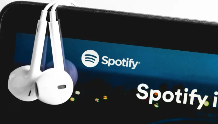 Słuchawki wiszące na ekranie smartfona z logo Spotify.
