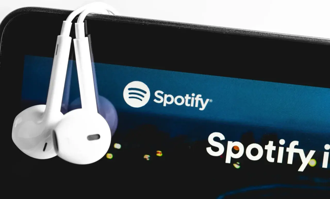 Słuchawki wiszące na ekranie smartfona z logo Spotify.